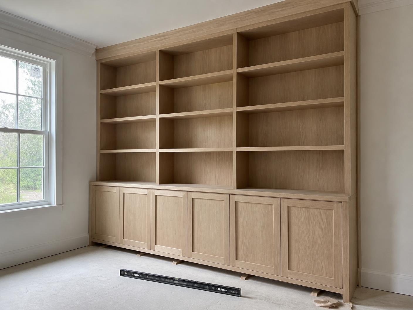 Built-in cabinetry being installed and scribed in an empty room